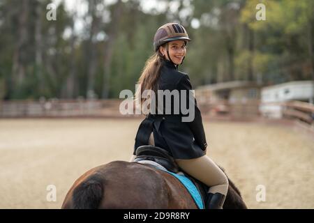 donna equitazione, sella inglese, in arena circondata da querce Foto Stock