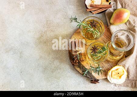 Sidro di pera o mela in bicchieri e bottiglia con rosmarino, cannella e pere biologiche fresche. Bevanda di frutta fermentata. Messa a fuoco selettiva. Vista dall'alto. Foto Stock