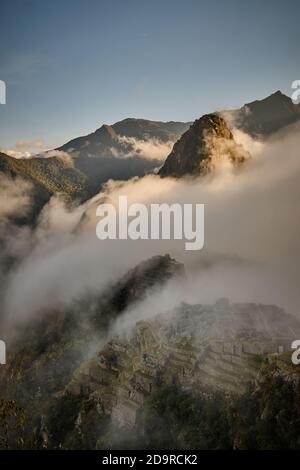 Alba Alba: La nebbia a bassa nube rotola sopra Machu Picchu e Huayna Picchu, Perù Foto Stock