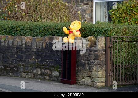 Un orsacchiotto siede sulla parete della casa che sventola ai passanti. Foto Stock