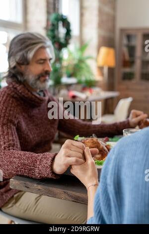 Mani di giovane donna e di uomo maturo che pregano prima Cena di Natale Foto Stock