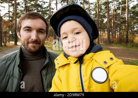 Allegro ragazzino e suo giovane padre in casualwear godendo weekend chill Foto Stock