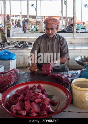 Uomo in abiti tradizionali pulizia di pesce umido in Barka Fishmarket, Oman Foto Stock