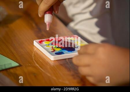 Tempera colorata utilizzata da un bambino durante le sue attività di apprendimento Foto Stock