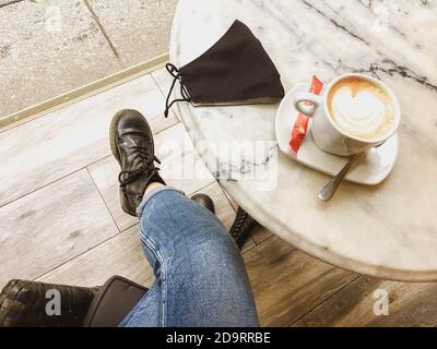 donna che ha un caffè in un bar con la maschera Foto Stock