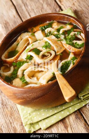 Frittatensuppe zuppa di pancake a fette da vicino in un piatto sul tavolo. Verticale Foto Stock