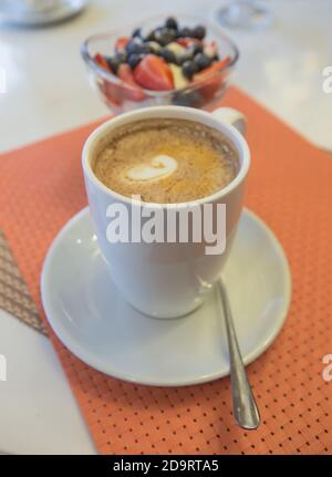 cappuccino e gelato con frutti di bosco sul tavolo nella caffetteria Foto Stock