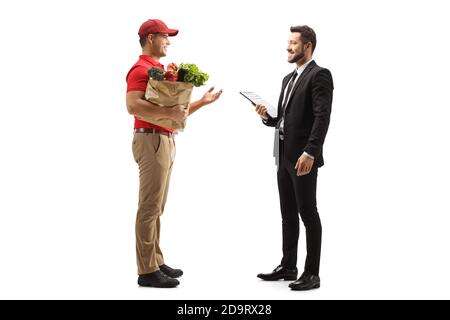 Foto di profilo a lunghezza intera di un corriere di consegna con un borsa della spesa che parla con il manager isolato su sfondo bianco Foto Stock