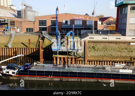 Neuss, Germania - Novembre 11. 2020: Vista sul vecchio molo storico del porto di imbarco interno con nave sul fiume reno, gru e fabbriche Foto Stock