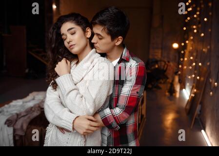 Sentimentale coppia felice in amore, l'uomo abbracciando la sua ragazza trascorrere le vacanze invernali a casa in calda atmosfera di natale Foto Stock