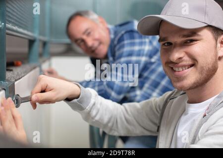 felice giovane lavoratore allacciare la maniglia a una finestra di plastica Foto Stock