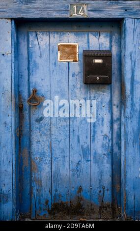 antica porta blu sbiadita dal tempo, con una cassetta postale nera e una maniglia ocra Foto Stock