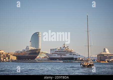 Barcellona, Spagna, settembre 2019. Una barca a vela che naviga nel porto di fronte ad un cantiere navale con l'hotel W sullo sfondo. Foto Stock