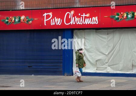Un membro del pubblico cammina davanti a un negozio 'puro natale' chiuso a Glasgow, Scozia, Regno Unito durante la pandemia del coronavirus - Novembre 2020 Foto Stock