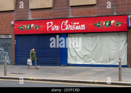 Un membro del pubblico cammina davanti a un negozio 'puro natale' chiuso a Glasgow, Scozia, Regno Unito durante la pandemia del coronavirus - Novembre 2020 Foto Stock