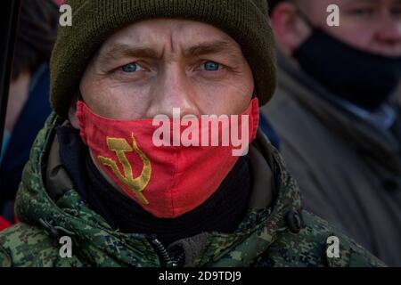 Mosca, Russia. 7 novembre 2020 UN uomo che indossa una maschera facciale con un simbolo per il lavoro all'interno dell'Unione Sovietica è visto in Piazza Rossa durante una processione in scena dai comunisti di Russia che segnano il 103° anniversario della rivoluzione bolscevica del 1917 ottobre sulla Piazza Rossa nel centro di Mosca, Russia Foto Stock