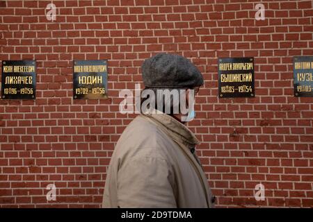 Mosca, Russia. 7 novembre 2020 UN uomo guarda le bandiere con i nomi della politica sovietica al Muro del Cremlino, dove i leader di stato sovietici sono sepolti, nel centro di Mosca, Russia Foto Stock