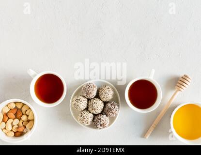 Palline di energia di caramelle crude fatte in casa con mandorla, anacardi, burro di arachidi e nocciole sul piatto con tazze da tè piatto posare su sfondo grigio con copia spa Foto Stock