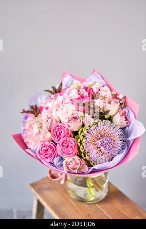 bouquet viola e rosa con il fiore del carciofo. Bellissimi fiori su tavolo di legno. Concetto di floristry. Primavera colori. Il lavoro del fiorista Foto Stock