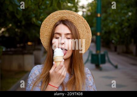 Ragazza in cappello che gode di gelato all'aperto in estate. Foto Stock