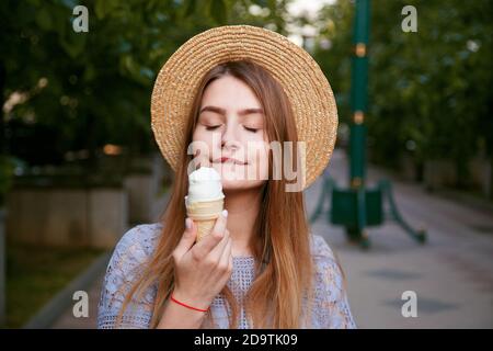 Ragazza in cappello che gode di gelato all'aperto in estate. Foto Stock