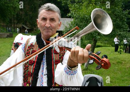 Contea di Brasov, Romania. Uomo in costume tradizionale che suona il violino rumeno. Foto Stock