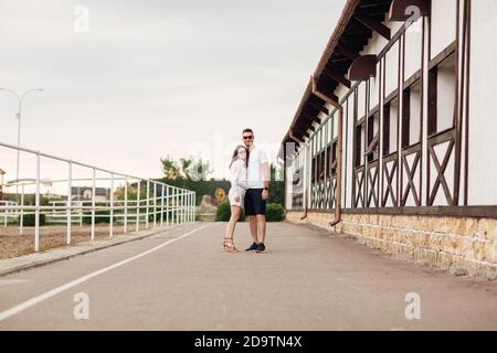 felice giovane uomo e donna si abbracciano e si divertono all'aria aperta in una calda giornata estiva. coppia a piedi vicino cavallo rancho Foto Stock