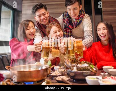 felici gli amici che bevono e tostano birra al ristorante hot pot Foto Stock