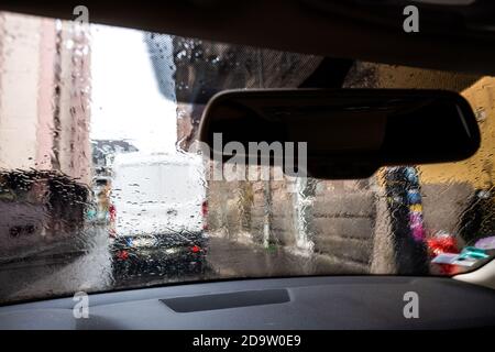 Vista attraverso il parabrezza dell'auto con gocce di pioggia in autunno A Parigi, con furgone bianco in posizione di parcheggio davanti Foto Stock