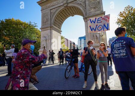 Una donna che indossa una maschera per il viso ha un cartello che dice "abbiamo vinto" mentre New York City erutta per celebrare la vittoria di Biden come 46esimo presidente degli Stati Uniti al Washington Square Park di New York. Foto Stock