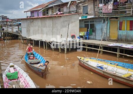 Pontianak, Kalimantan, Indonesia, febbraio 2016. Un padre e un figlio in una barca a remi su uno dei canali della città. Foto Stock