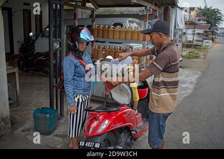 Pontianak, Kalimantan, Indonesia, febbraio 2016. Una donna si rifornisce di moto in un chiosco di strada. Foto Stock