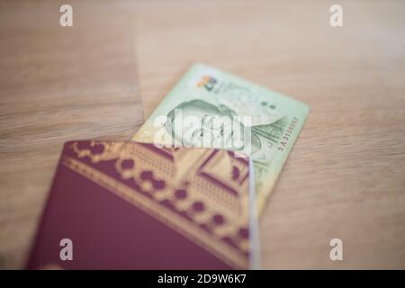 Twenty Thai Baht Bill in parte all'interno di un passaporto svedese Foto Stock