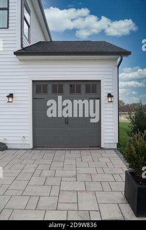 Porta singola grigia per garage per famiglie con tetto scuro pareti bianche luci per garage Foto Stock