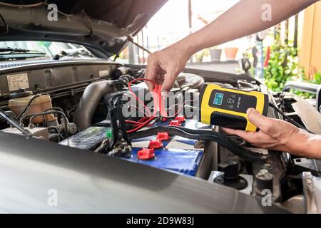 Il reparto tecnico utilizza lo strumento per misurare la tensione e la temperatura della batteria dell'auto. Foto Stock