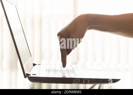 Il dito di un uomo d'affari sta premendo il pulsante della tastiera del computer portatile in ufficio. Foto Stock