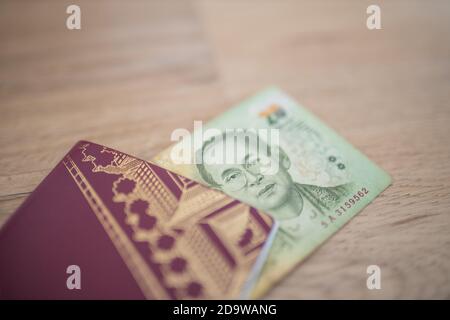 Twenty Thai Baht Bill in parte all'interno di un passaporto svedese Foto Stock