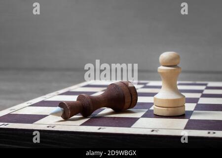 La fine del gioco degli scacchi, la pedina bianca sconfisse il re oscuro. Spazio di copia concetto aziendale, messa a fuoco selettiva. Foto Stock