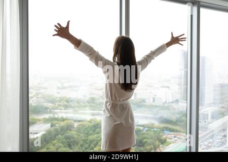 Donna affascinante in piedi alla parete della finestra che tende le mani ai lati Foto Stock