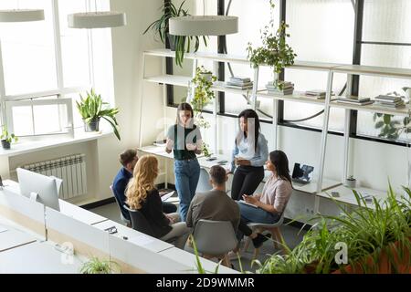 Gruppo di dipendenti diversi che ascoltano il leader del team femminile millenario Foto Stock