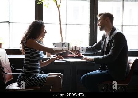 Soddisfazione cliente nero femmina handshaking con consulente maschile in caffetteria Foto Stock