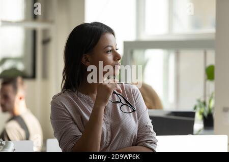 Dipendente femminile biraciale penoso millenario che si rompe guardando a distanza Foto Stock