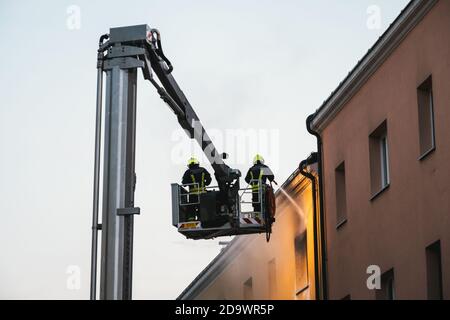 Amstetten, Austria - Settembre 20 2020: Vigili del fuoco austriaci che spengono un incendio in un edificio di appartamenti in fiamme da una piattaforma aerea di lavoro Foto Stock