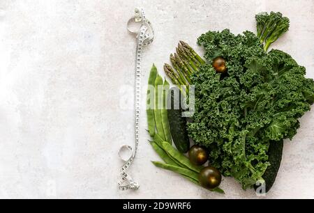 Dieta e sfondo sano con verdure verdi e metro nastro. Foto Stock