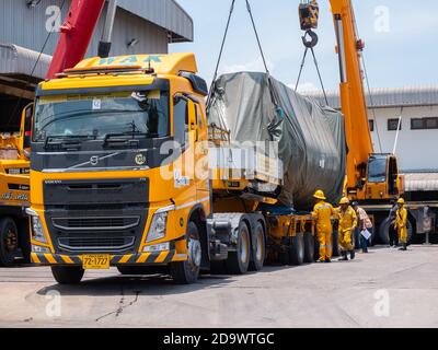 Autocarro per il trasporto pesante e due grandi gru mobili che caricano un grande essiccatore industriale per la spedizione in un'officina industriale a Samut Prakan, Thailan Foto Stock