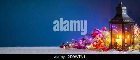 Composizione di Natale della lanterna ornamenti colorati sfere stelle candele e Abete rami sulla neve Foto Stock