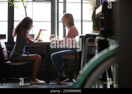 Due diverse giovani donne amiche che hanno una piacevole conversazione al bar Foto Stock