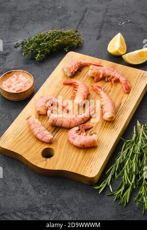 Code di gamberetti surgelate surgelate su tagliere di legno Foto Stock
