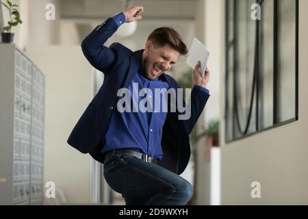 Euforico maschile executive jumping in ufficio corridoio ottenere crescita della carriera Foto Stock