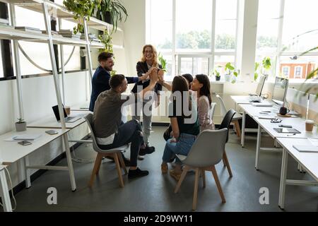 Personale multietnico e allenatore donna che accatastano le mani in alto cinque Foto Stock